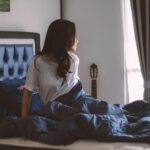 Donna che legge un libro a letto con una luce soffusa, rilassandosi prima di dormire.