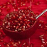 Semi di melograno freschi su uno sfondo bianco, pronti per essere gustati.