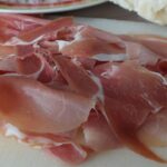 Immagine di un pacchetto di prosciutto crudo con un'etichetta rossa e avviso di salute.
